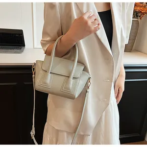 Close-up of elegant matte leather handbag styled with a minimalist light-colored suit