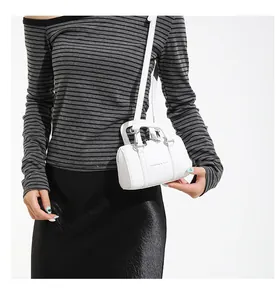Detailed view of white cylindrical Boston bag with top handle and fashion text strap