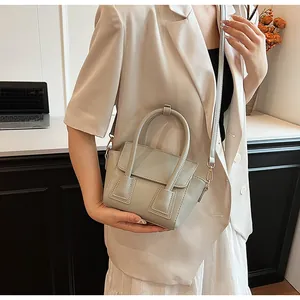 Detail of a grey chic crossbody bag showing the faux leather texture and gold metal clasp
