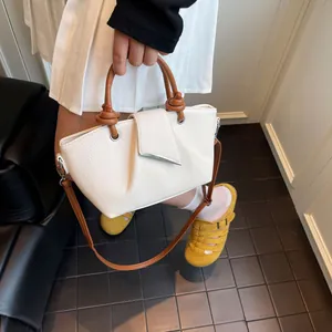 Detail of white lychee grain leather bucket bag with brown handle and silver metal buckle