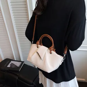 White ruched bucket bag with brown handles and shoulder strap in a minimalist setting