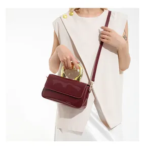 Detail of dark red patent leather bag featuring a gold heart-shaped metal handle