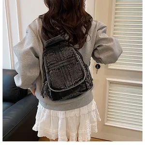Back view of a mini black washed denim backpack shown on a model for daily wear