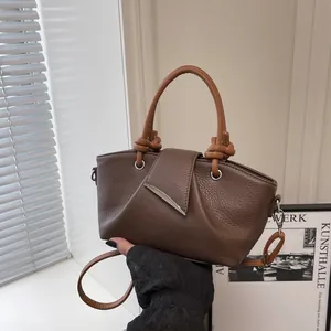 Detail of silver metallic wavy buckle on dark brown pleated leather bucket bag