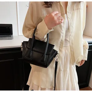 Detail of a black matte PU leather handbag with gold metal buckles and a long strap
