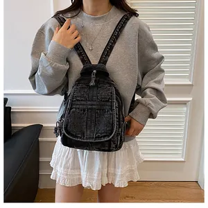 Close-up of vintage dark grey denim backpack with distressed finish and zip pocket detail