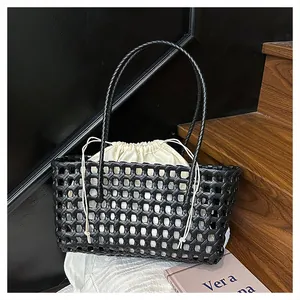 Détail du sac cabas tressé noir avec pochette beige sur fond intérieur minimaliste moderne