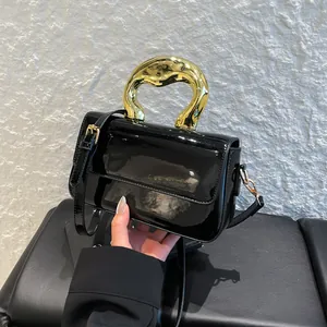 Fashionable black patent leather crossbody bag with artistic gold wave metal handle