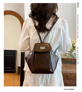 Detail view of deep brown leather backpack featuring silver buckles and multiple zippers
