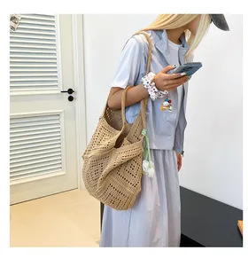 Detalle del bolso tote de tejido calado beige con colgantes decorativos de tulipanes blancos
