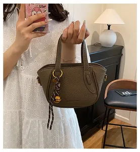 Detail der dunkelolivgrünen Ledertasche mit Lychee-Narbung und goldenem Glockenanhänger