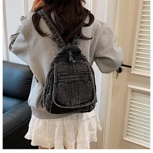 Detail of vintage gray denim backpack with multiple zipper pockets on a female model