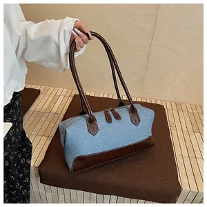 Détail du sac cabas en denim et cuir avec des coutures contrastées et une fermeture éclair