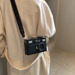 Vintage camera-shaped crossbody bag in black pebbled leather with 3D metallic lens detail