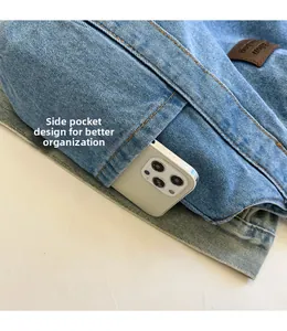 Detailed view of denim tote side pocket showing storage capacity with a smartphone