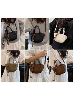 Detail der Litschi-Lederstruktur und gewebtem Kordel-Anhänger an dieser Handtasche