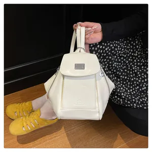 Detail of cream PU leather mini backpack showing magnetic flap and metal buckle accent