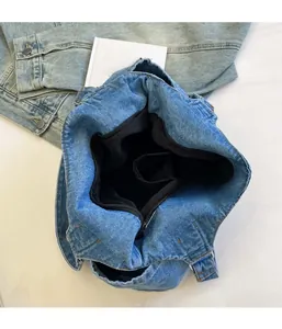 Internal view of denim tote bag showing black fabric lining, zipper and inner pockets