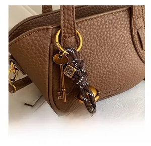 Nahaufnahme der Lederhandtasche mit Vintage-Goldanhängern und genarbter Struktur