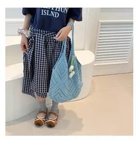 Detalle del bolso tote de ganchillo azul claro con colgante de tulipán y tejido geométrico