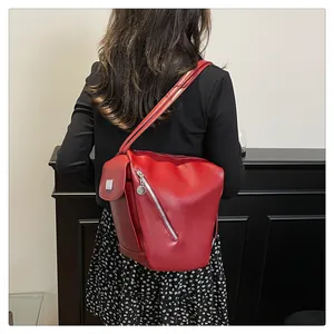 Detailed view of red leather multi-pocket backpack with silver zippers and metal hardware
