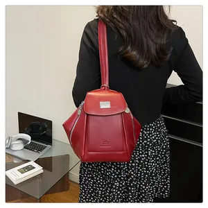 Detailed close-up of a red leather backpack showing premium texture and metal accents