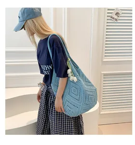 Detalle del bolso tote de punto azul claro con patrones geométricos y colgante de tulipán