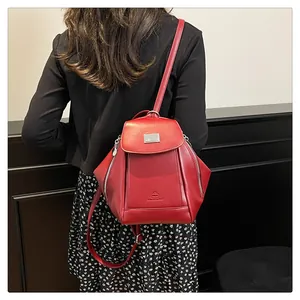 Detail view of red PU leather backpack with silver metal buckle and side zipper accents