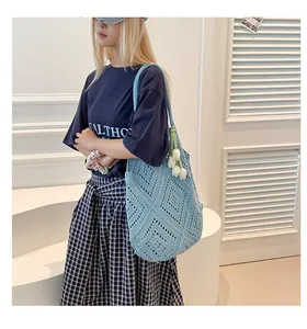 Bolso tote de ganchillo azul con colgante de tulipán llevado por modelo en estudio