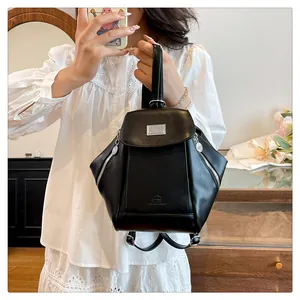 Detailed close-up of a black leather mini backpack with silver metal buckle and side zipper