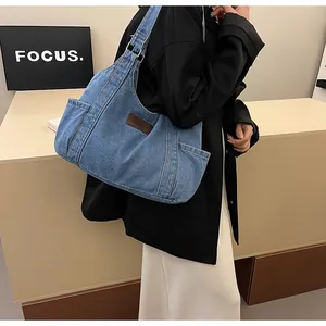 Detail of blue denim tote bag featuring side pockets and a brown leather logo patch