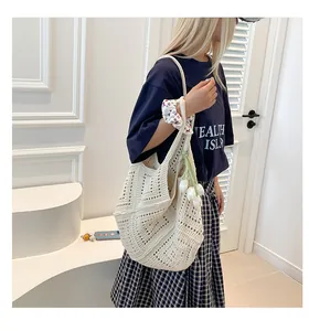 Detalle del bolso tote de punto calado blanco con colgante de tulipán y adorno