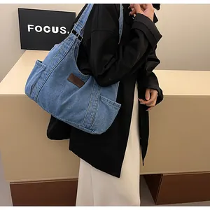 Detail of light blue denim tote bag with side pockets shown in a casual lifestyle setting