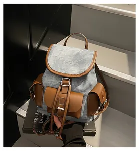 Detail of vintage denim backpack showing leather flap with buckle and printed lettering