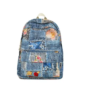 Blue denim mini backpack with floral embroidery and quilted patterns on white background