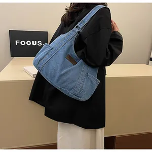Detail of blue denim tote bag showing washed fabric texture and leather side patch
