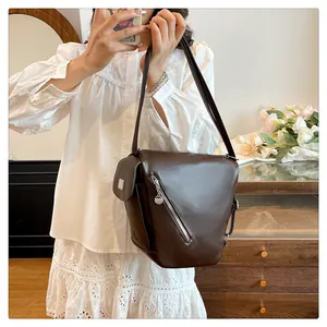 Detail of dark brown leather shoulder bag with silver zippers and side pocket on model