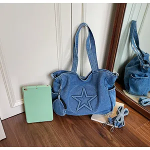 Detail of blue denim tote bag with embossed star pattern, mini pouch and long strap