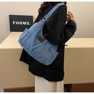 Detail shot of the blue denim tote bag side pocket and fashion label on shoulder