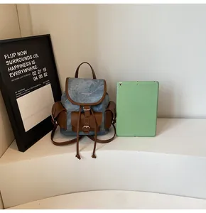 Detailed view of denim and leather vintage backpack on a white pedestal with tablet accessory