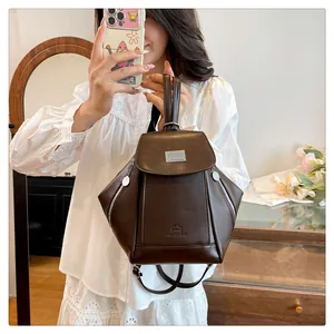 Detail of dark brown faux leather mini backpack featuring side zippers and top handle