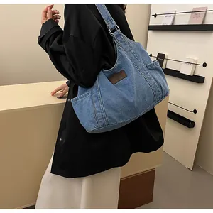 Detail of blue denim tote bag featuring a brown leather patch and side pocket