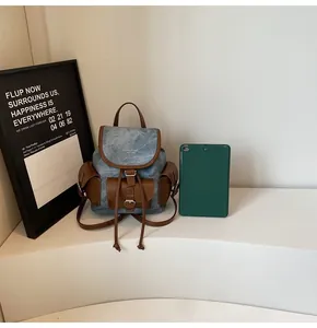 Detail of blue denim mini backpack with brown leather trim and metal buckles