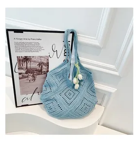 Detalle de bolso tote de ganchillo azul claro con patrón calado y colgantes de tulipán