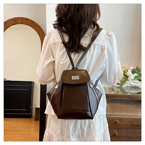 Close-up of a dark brown faux leather backpack featuring a silver metal flap and embossed logo