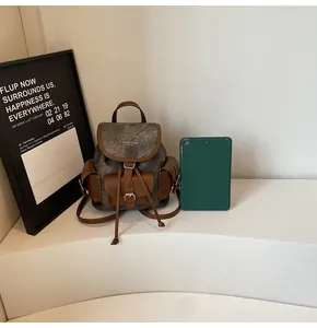 Close-up of vintage sage green backpack with leather straps and logo detail