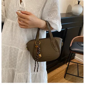 Detail der olivbraunen Handtasche aus Leder mit Lychee-Muster und Vintage-Anhänger