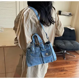 Détail du sac bandoulière en denim délavé vintage avec poches cargo et boucles en métal