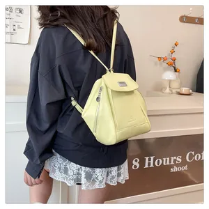 Detail of light yellow synthetic leather backpack with side zippers and embossed logo