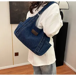 Detail of blue denim hobo bag with adjustable strap and leather patch for women